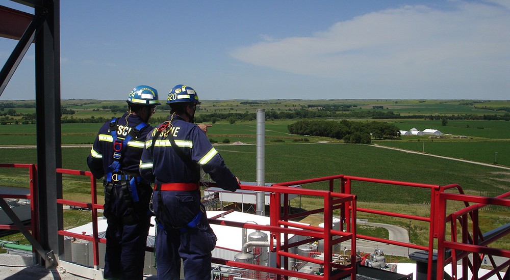 2 Rescuers on top of a grain silo overlooking an ethanol plant